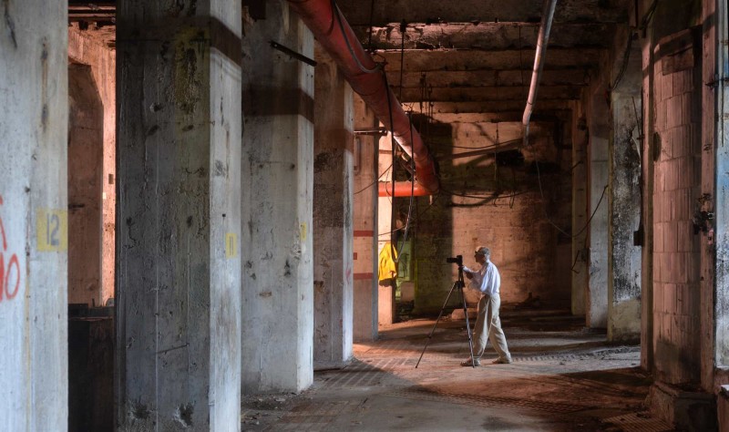 Le bénévole Bill Woodley travaille parmi les imposants piliers de béton au sous‑sol qui, autrefois, supportaient les machines massives de l’usine se trouvant à l’étage. 